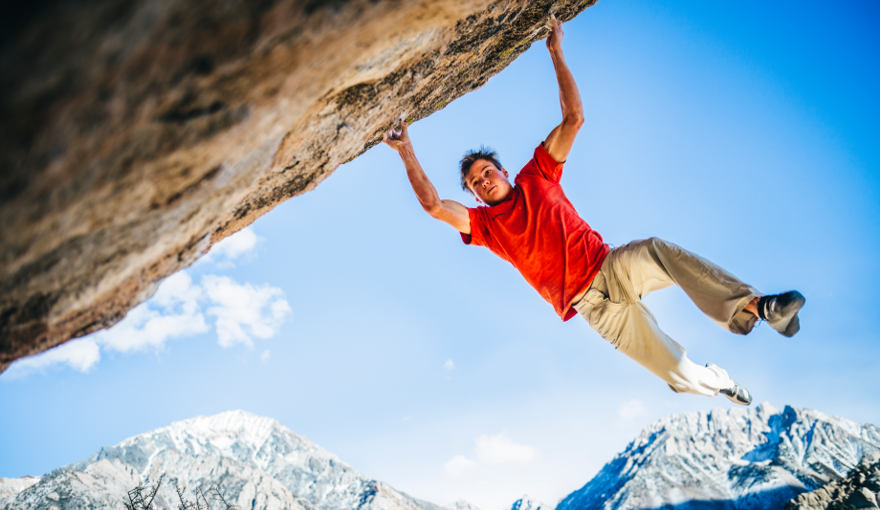 Alex Magos swinging on a boulder wearing Tenaya Masai climbing shoes