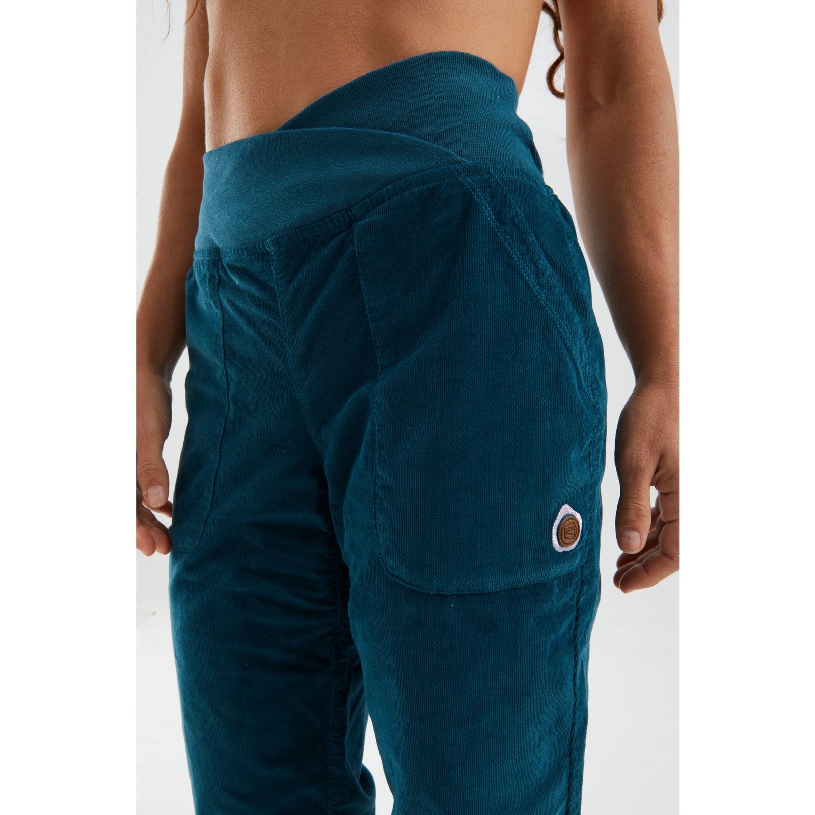 Teal pants worn by a person on a white background