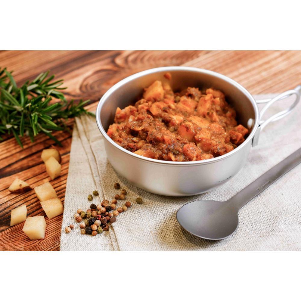 Beef and Potato Hotpot in a silver pan with a spoon and herbs surrounding it