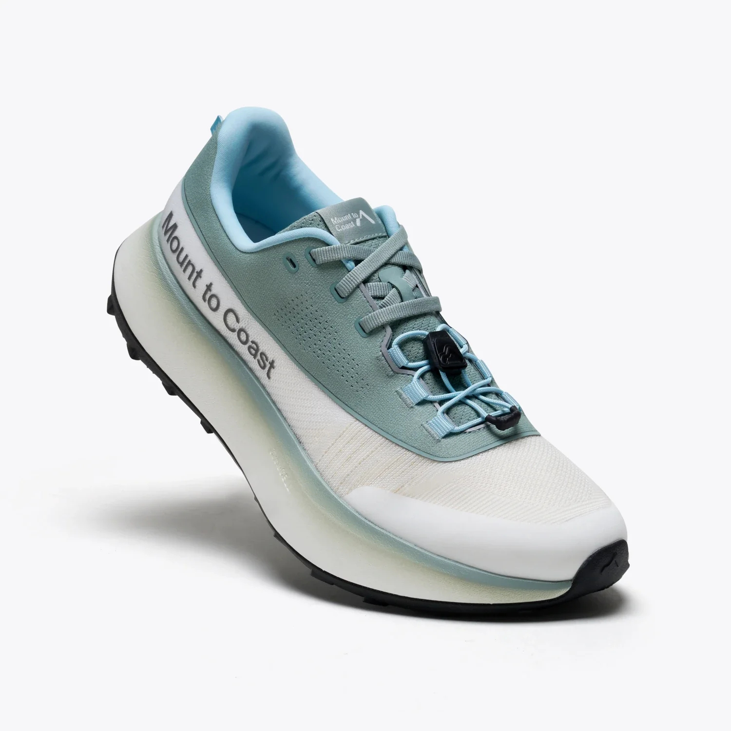 A single athletic trail running shoe from Mount to Coast, shown from a three-quarters angle on a light gray studio background. The shoe features a white mesh upper, a dusty blue suede overlay, light blue laces, a blue interior lining, and a thick white and translucent gray midsole with a black outsole.