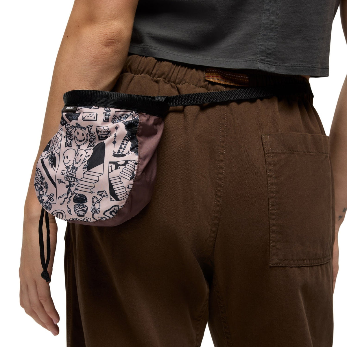 Person wearing a patterned fanny pack on a plain background