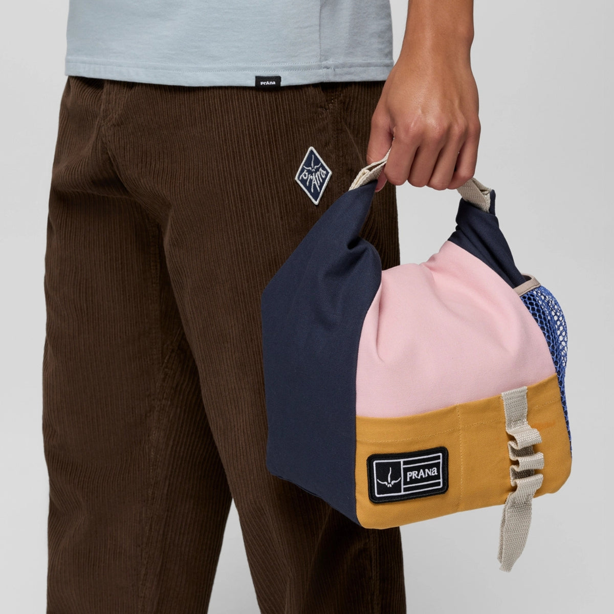 Person holding a colorful bag with multiple compartments on a plain background