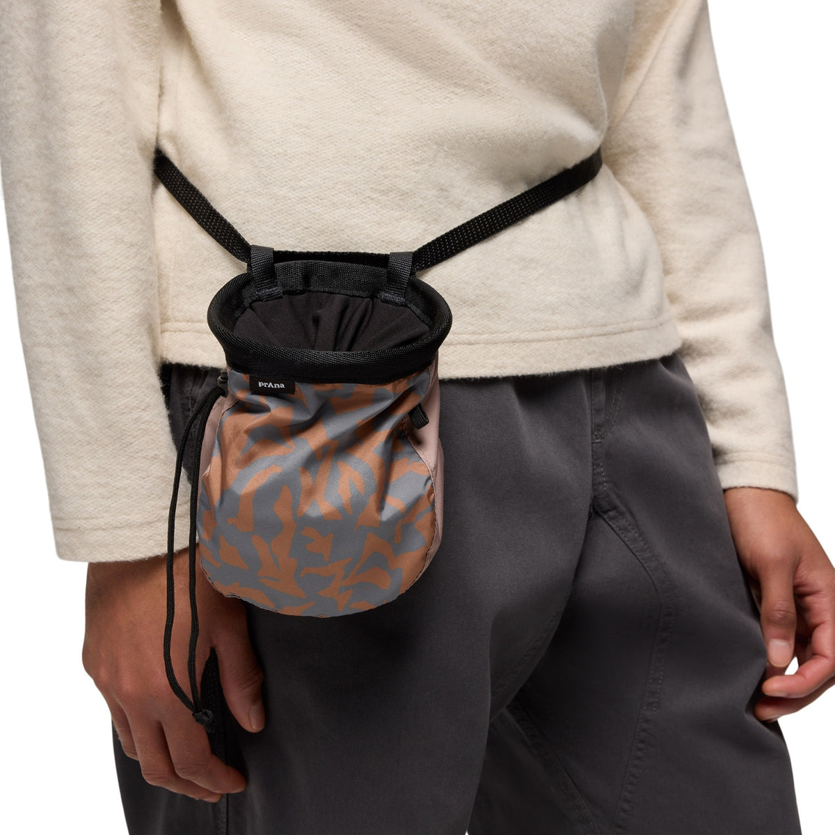 Person wearing a camouflage waist bag on a plain background