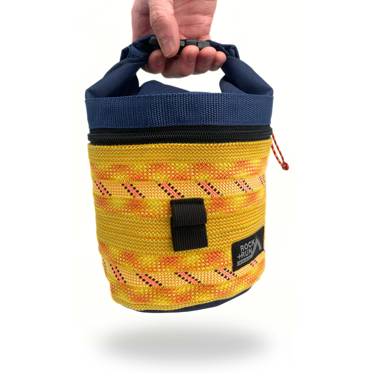 Yellow chalk bag with blue top held by a hand on a white background
