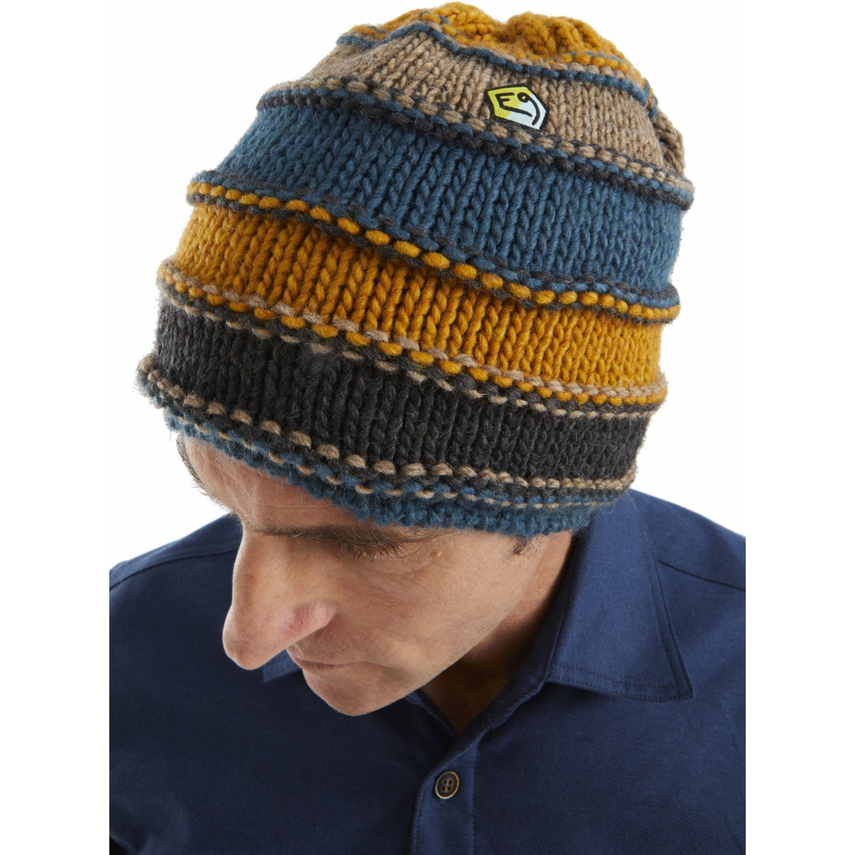 Person wearing a striped knit beanie with a logo on a white background