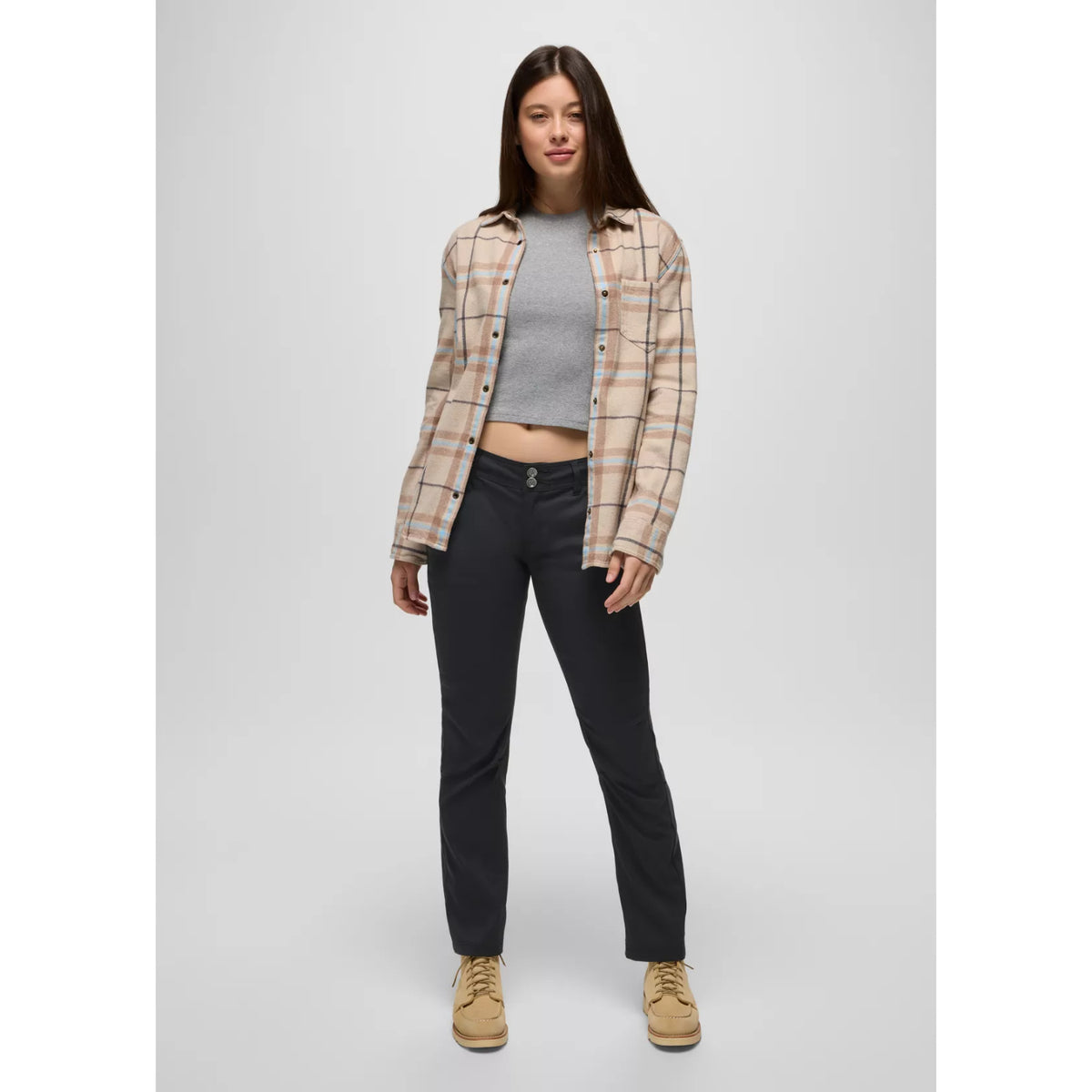 Woman wearing a plaid shirt, gray top, black pants, and beige shoes on a light gray background