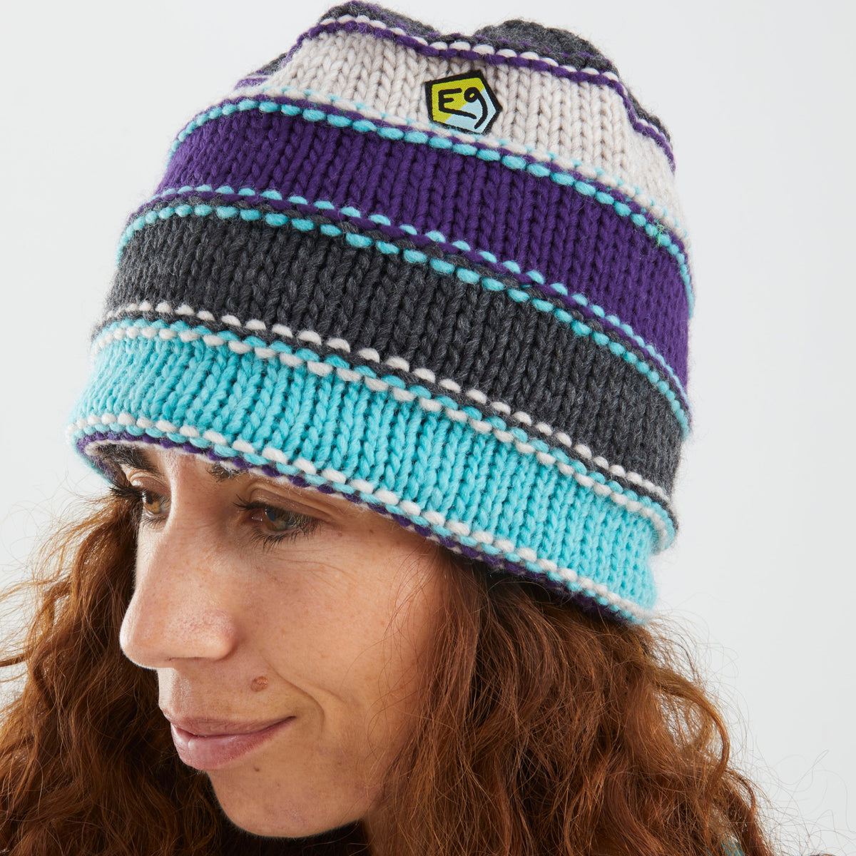 Person wearing a striped beanie with a logo on a white background