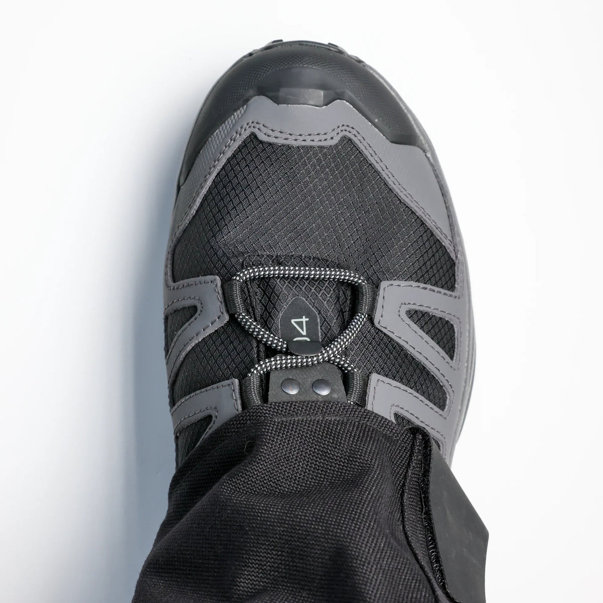 Close-up of a black and gray shoe with a brand logo on a light gray background