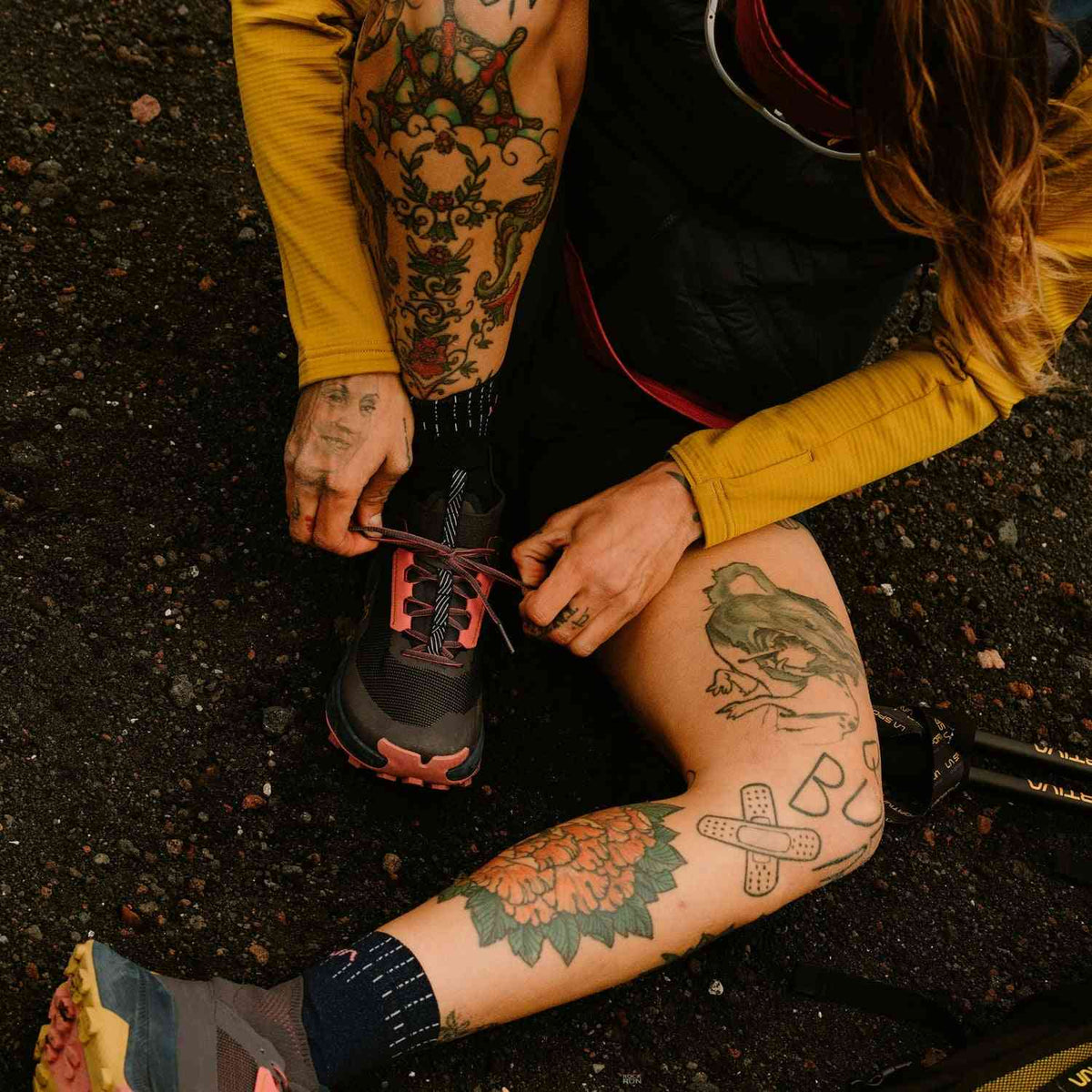 La Sportiva Prodigio Hike GTX - Men's fast hiking boots with GORE-TEX, shown on a tattooed hiker lacing up on rugged terrain. Ideal for speed hiking.