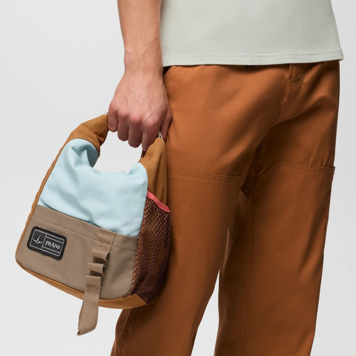 Person holding a brown bag with a visible brand logo against a plain background