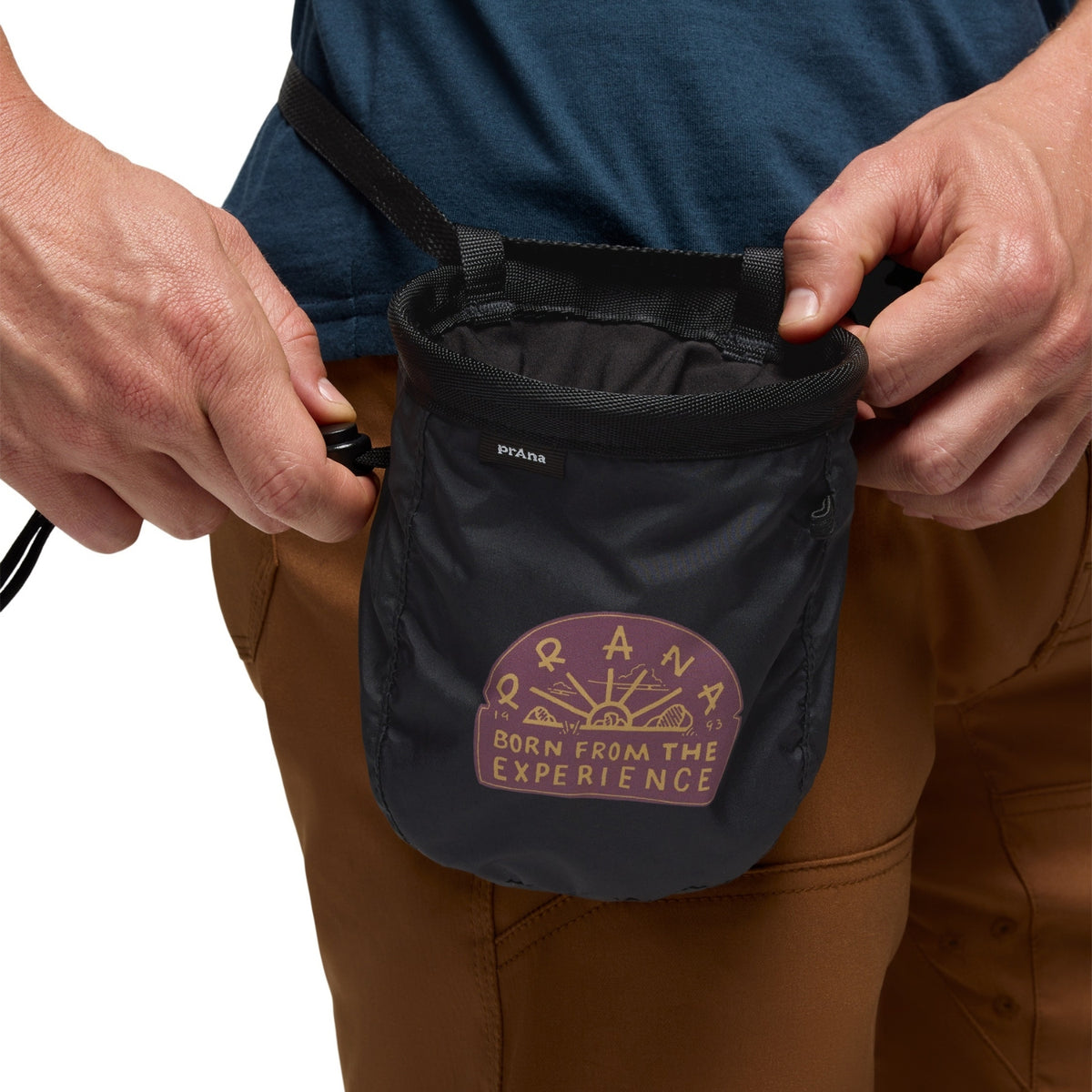 Person holding a black Prana chalk bag with a logo on a white background