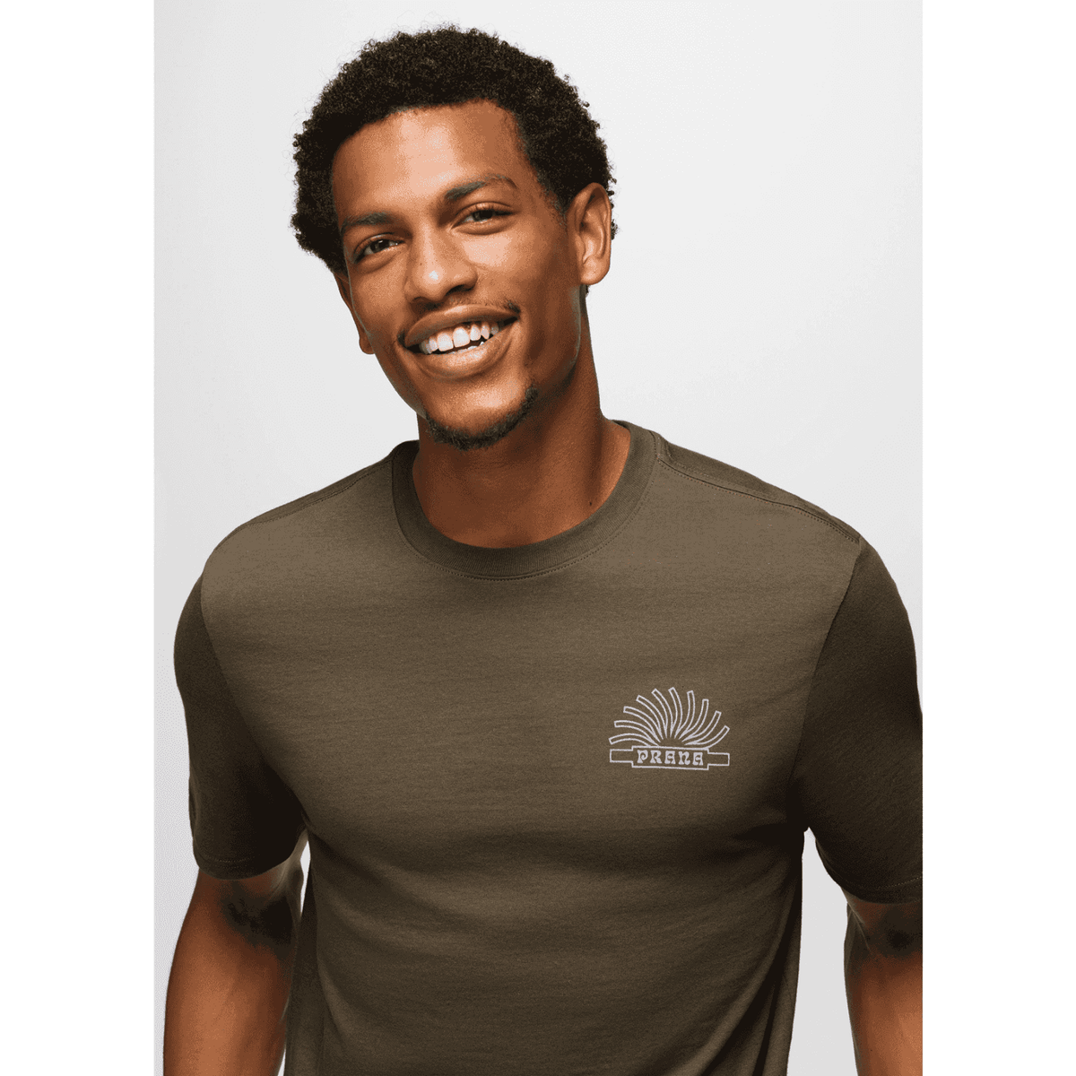 Model smiling in Prana Lands Beginning T-Shirt highlighting front chest graphic and soft organic cotton texture.