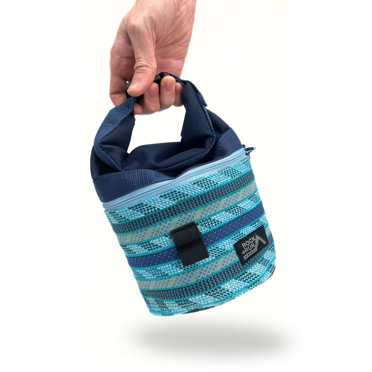 Blue and black striped chalk bag held by a hand on a white background