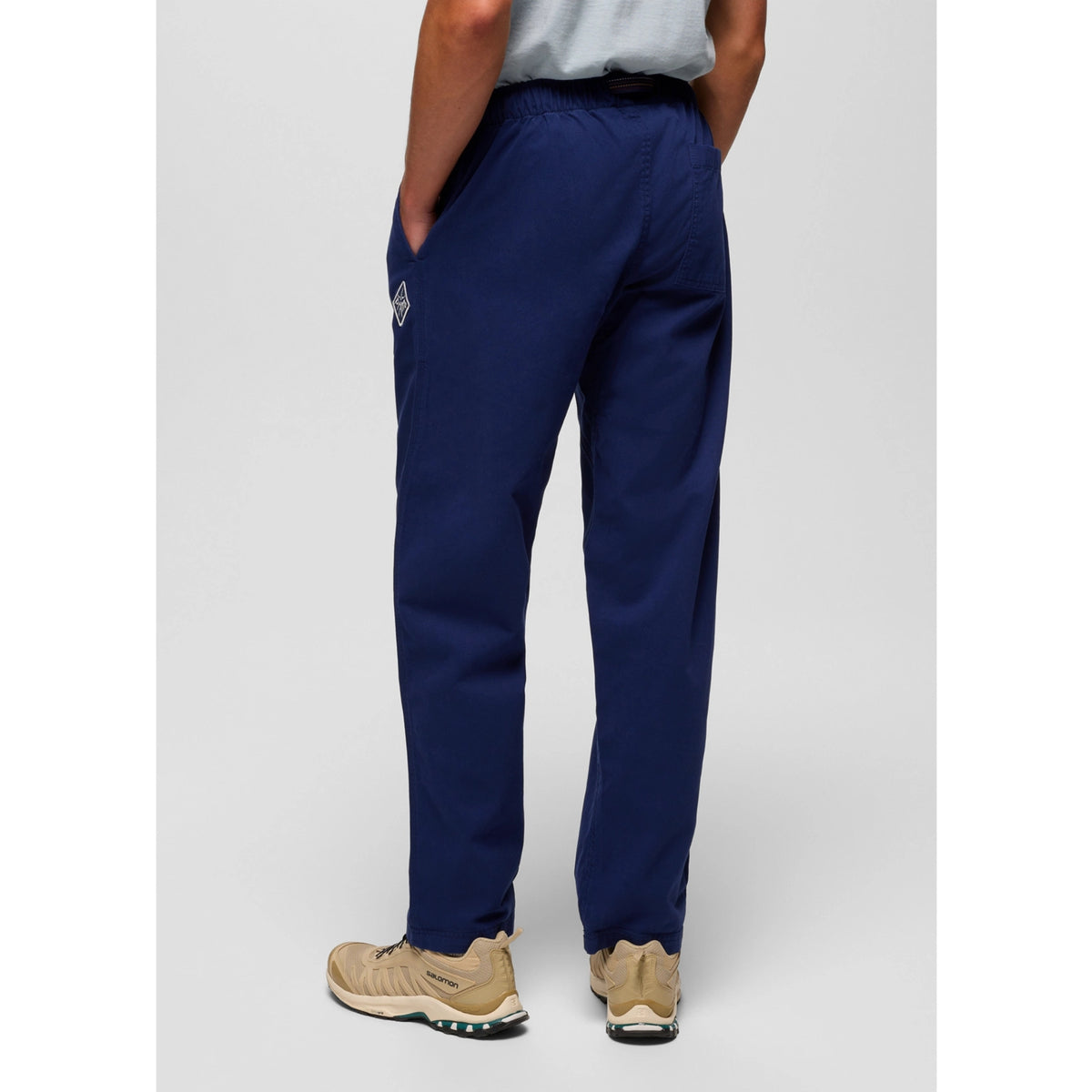 Person wearing navy blue pants with a logo on a light gray background