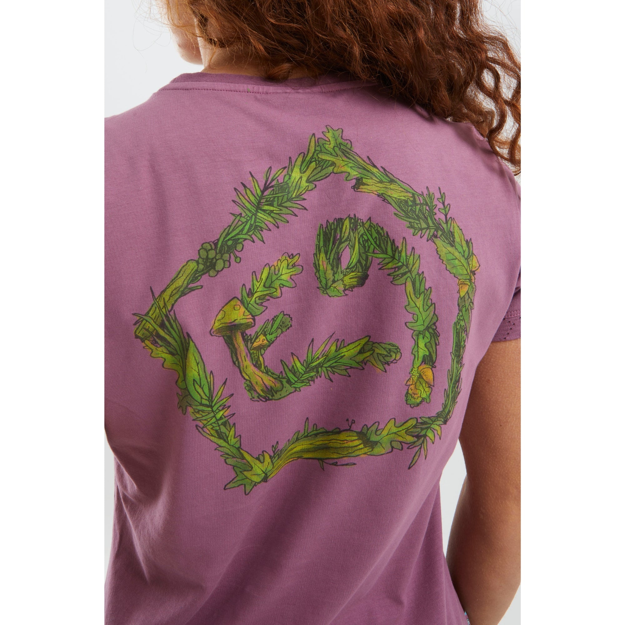 Purple t-shirt with green leafy design on the back, worn by a person.