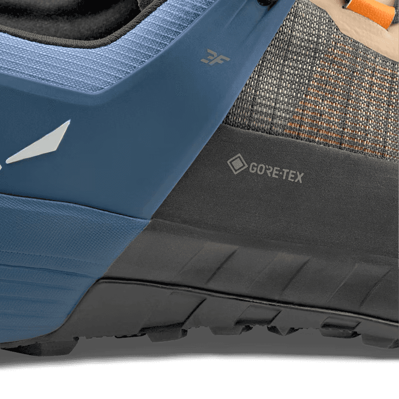 Close-up of a blue and black shoe with GORE-TEX branding on a textured surface.