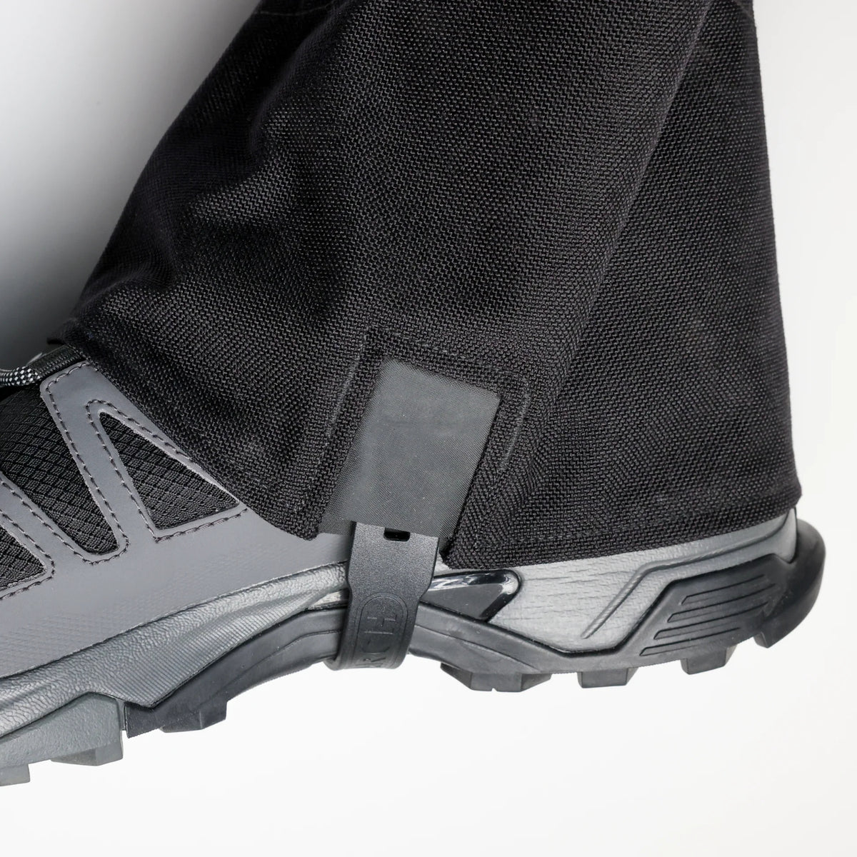 Close-up of a gray hiking boot with a gaiter on a white background