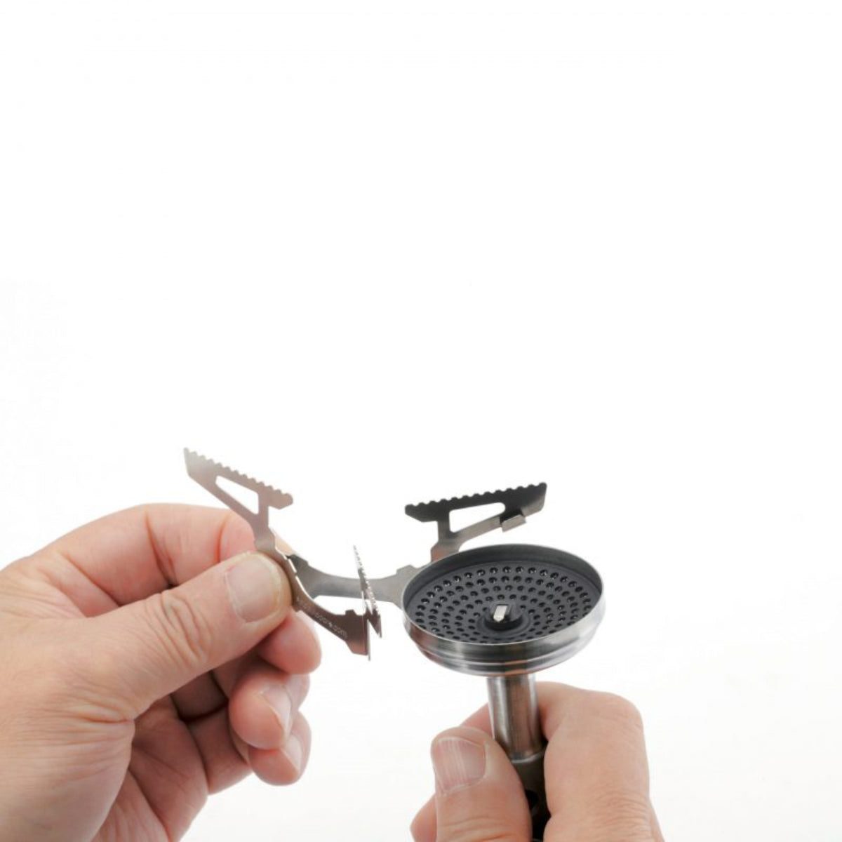 Hand holding a small metal stove with a white background