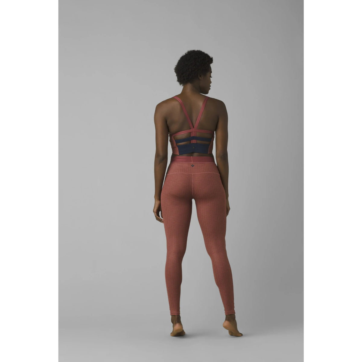 Person wearing a pink outfit with a black and blue top on a gray background