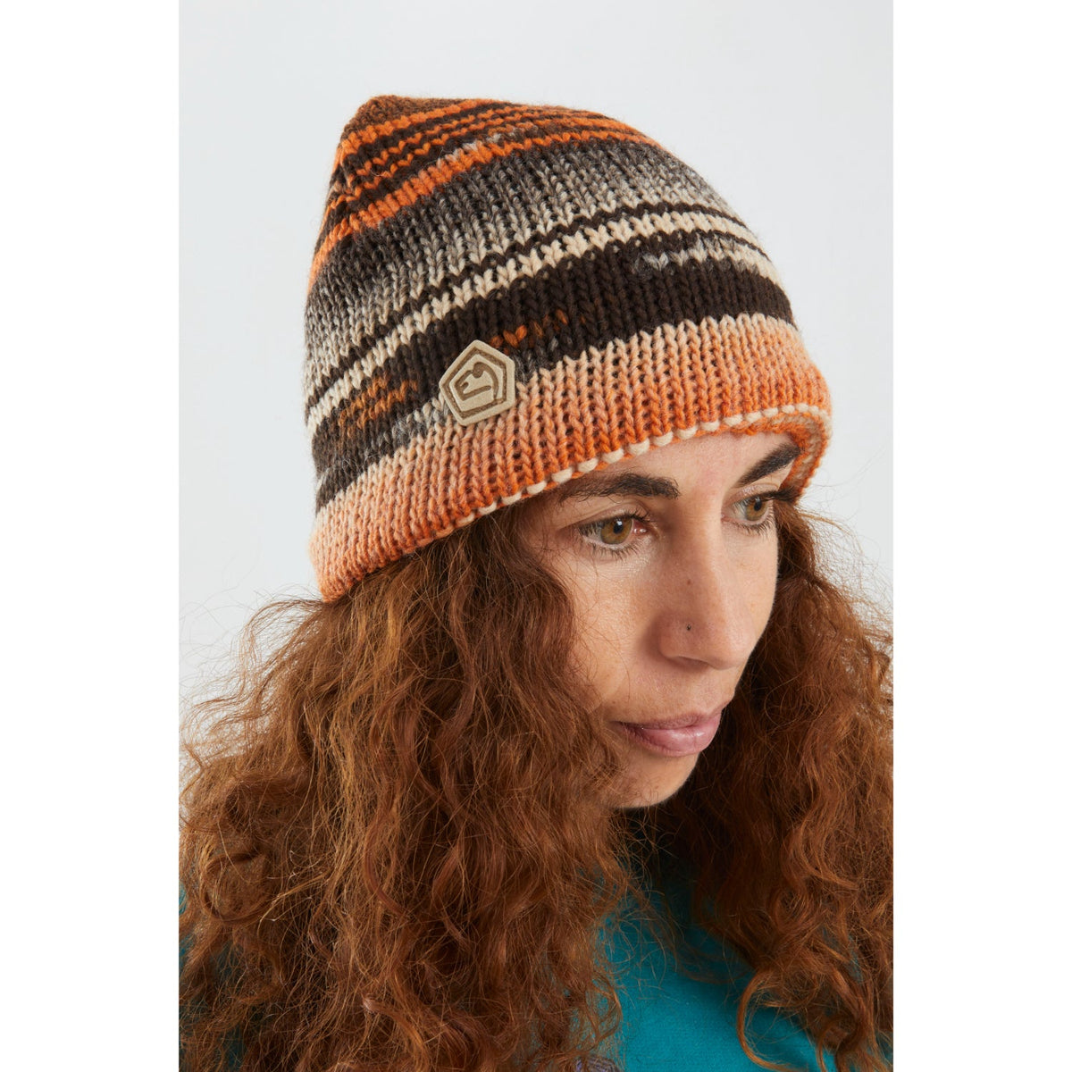 Woman wearing a striped beanie with a brand logo on a white background