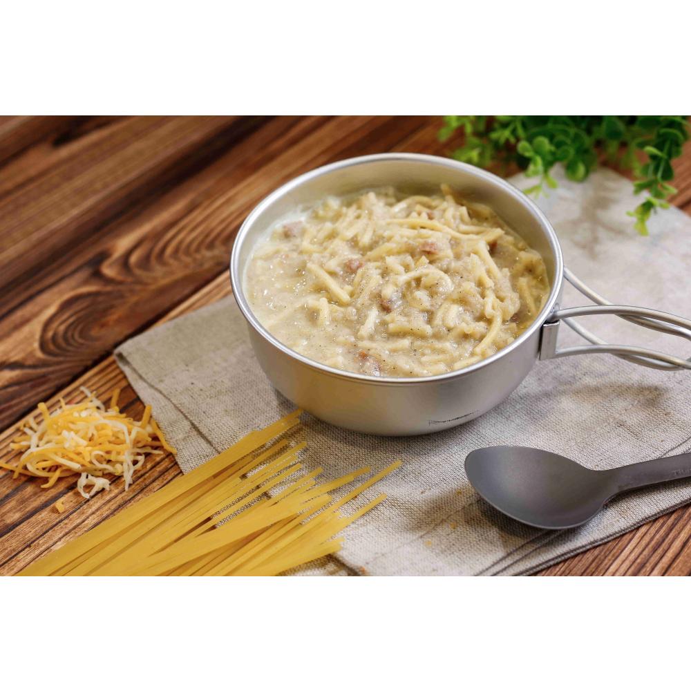 Expedition Foods Spaghetti Carbonara shown in a bowl next to a spoon and fresh ingredients